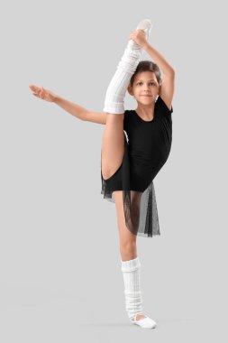 Little girl doing gymnastics on light background