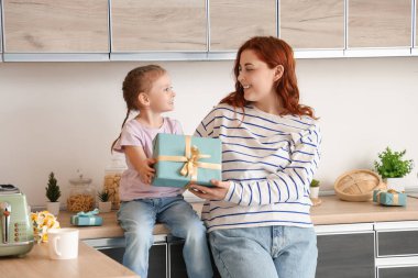 Little girl and her mother with present in kitchen. Mother's Day