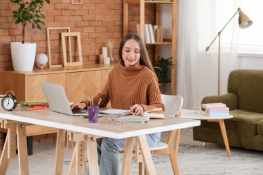 Female tutor with laptop and notebooks giving online lesson at home