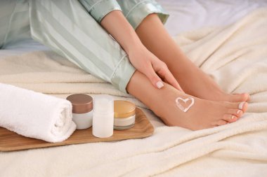 Woman with heart made of cream on her foot in bedroom, closeup