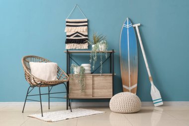 Oturma odasının içinde sörf tahtası, raf ünitesi ve koltuk var.