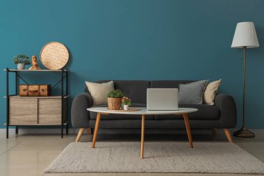 Interior of cozy living room with sofa, coffee table and shelving unit near blue wall