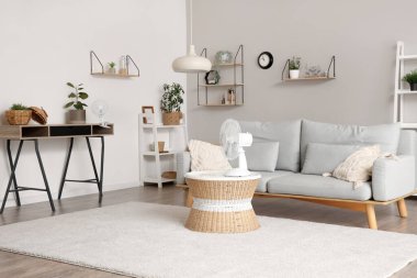 Interior of stylish living room with electric fans on table