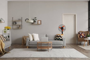Interior of stylish living room with floor electric fan and laptop