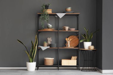 Mutfak gereçleri ve karanlık duvarın yanındaki bitkilerle raflarda.