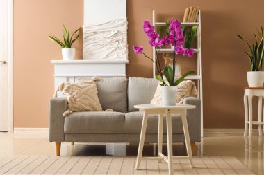 Interior of stylish living room with sofa and orchid flower on table