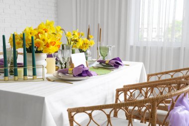 Beautiful table setting with daffodils and candles for wedding celebration in room