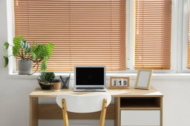 Floraryumlu dizüstü bilgisayar ve hafif ofisteki masada bitki.