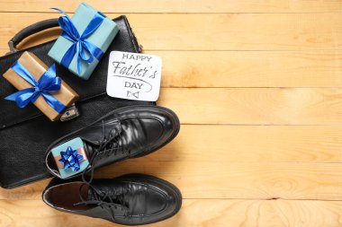 Gift boxes, greeting card with text HAPPY FATHER'S DAY and man's accessories on yellow wooden background. Top view