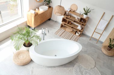 Interior of light bathroom with ceramic bathtub and houseplants, top view