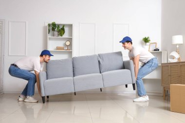 Loaders carrying sofa in room