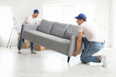 Loaders carrying sofa in room
