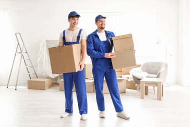Loaders carrying cardboard boxes in room