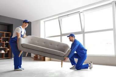 Loaders carrying couch in room
