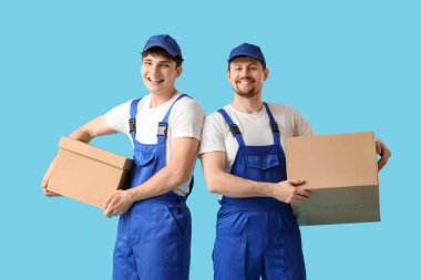 Loaders carrying cardboard boxes on blue background