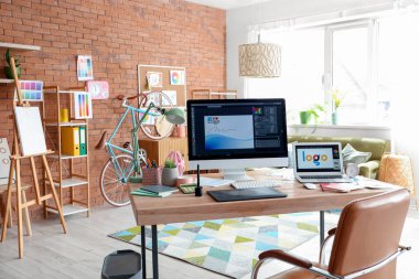 Graphic designer's workplace with computer monitor and laptop in office