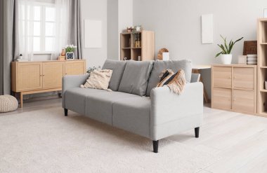 Modern oturma odasının iç kısmında şık minderleri olan gri kanepe.