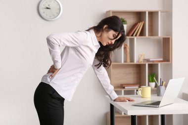 Beautiful young businesswoman suffering from back pain at office