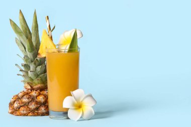 Mavi arka planda çiçek olan bir bardak taze ananas suyu.
