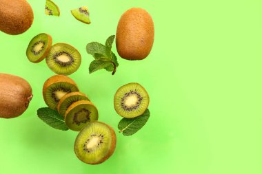 Yeşil arkaplanda kivi ve nane yaprakları uçuşuyor