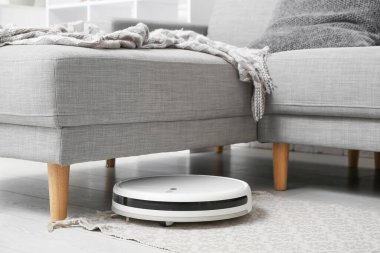 Evdeki koltuğun altındaki modern robot süpürgesi.