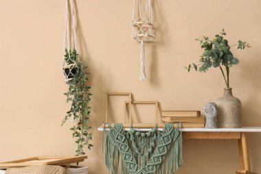 Ofiste bej duvarın yanında çerçeveli, kitaplı ve duvar halılı masa.