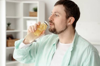 Young man drinking lemon water at home, closeup