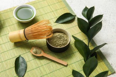 Beyaz arka planda chasen ile bir kase kibrit çayı ve pudra.