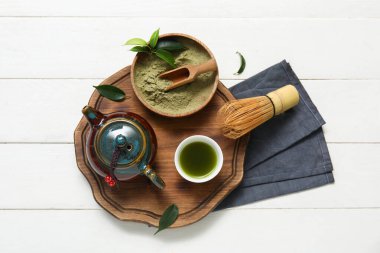 Beyaz ahşap arka planda bir kase kibrit çayı ve pudra.