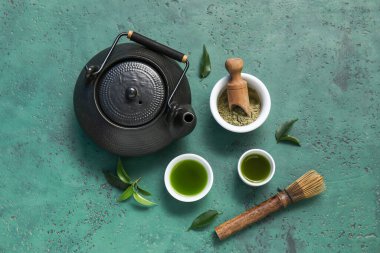 Yeşil zemin üzerinde chasen olan bir kase kibrit çayı ve pudra.