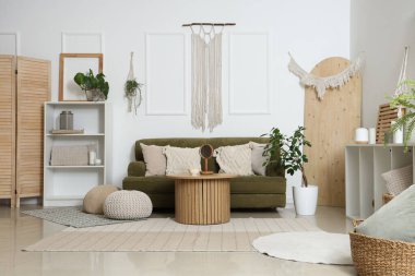 Interior of light living room with green sofa and wall tapestry