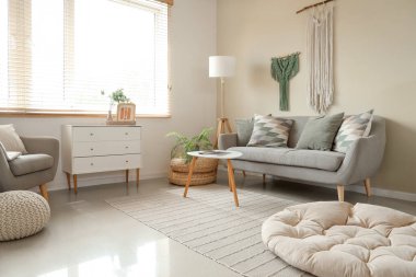 Interior of cozy living room with sofa, drawers and wall tapestries
