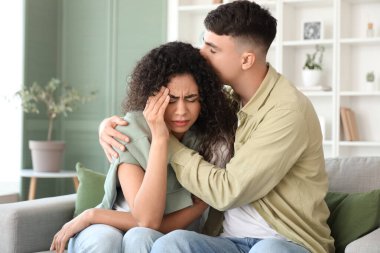 Sad troubled young couple sitting on sofa at home