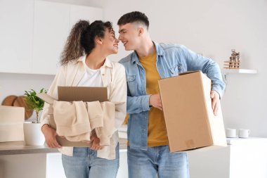 Happy young couple with moving boxes at new home