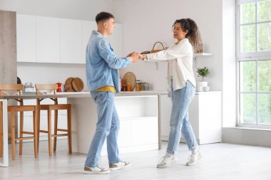 Happy young beautiful couple dancing in kitchen at home