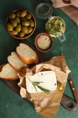 Lezzetli peynirli ahşap tahta, biberiye ve yeşil arka planda ekmek dilimleri.