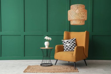 Kahverengi koltuk ve yeşil duvarın yanında çiçekli kahve masası