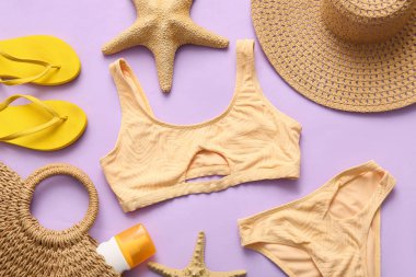 Composition with stylish female swimsuit and beach accessories on lilac background