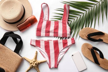 Composition with stylish female swimsuit, beach accessories and modern mobile phone on white background
