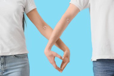 Blood donors with applied patches making heart gesture on blue background, closeup clipart