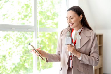 Female reporter with microphone and notebook in studio