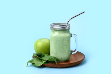 Mason kavanozu taze ıspanaklı smoothie ile mavi arka planda elma