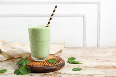 Beyaz ahşap masada taze ıspanaklı smoothie.