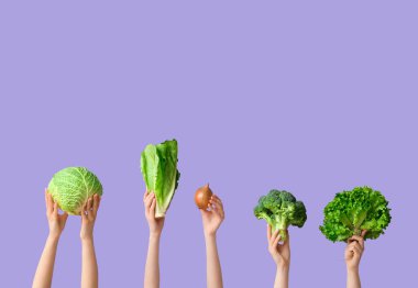 Female hands holding fresh vegetables on lilac background