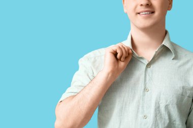 Young man in stylish collar shirt on blue background