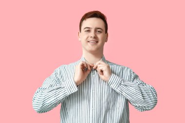 Handsome young man in stylish striped collar shirt on pink background