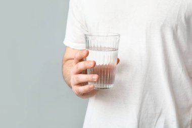 Young man with glass of clean water on grey background