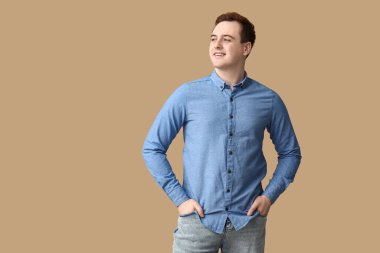 Handsome young man in stylish blue collar shirt on brown background