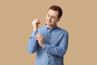 Handsome young man in stylish blue collar shirt on brown background