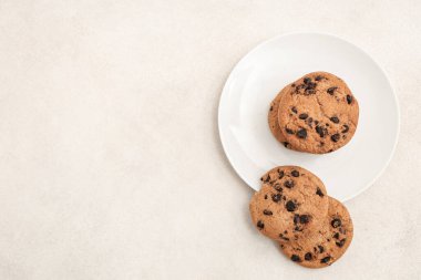 Beyaz arka planda çikolata parçacıklı bir tabak tatlı kurabiye.